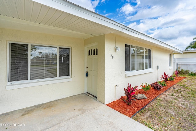 doorway to property with fence and stucco siding