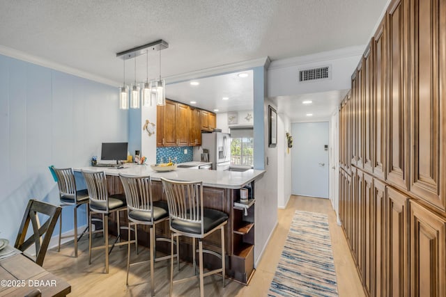 721 S Beach St Unit 215A, Daytona Beach, FL 32114 - kitchen featuring white fridge with ice dispenser, brown cabinetry, open shelves, a kitchen breakfast bar, and light wood-style floors