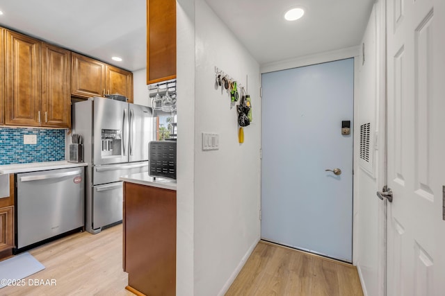 721 S Beach St Unit 215A, Daytona Beach, FL 32114 - kitchen with appliances with stainless steel finishes, light wood finished floors, light countertops, decorative backsplash, and brown cabinetry