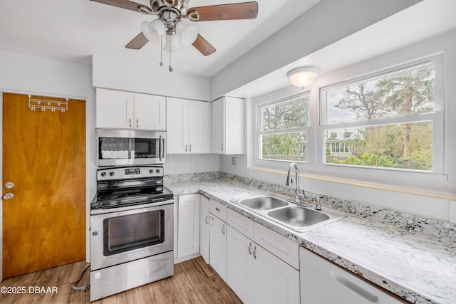 kitchen with light wood-style flooring, a sink, white cabinetry, a ceiling fan, and appliances with stainless steel finishes