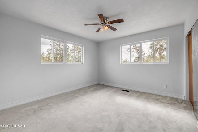 empty room with baseboards, ceiling fan, and light colored carpet