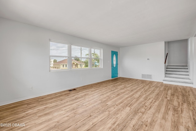 unfurnished living room with light wood finished floors, stairs, and visible vents