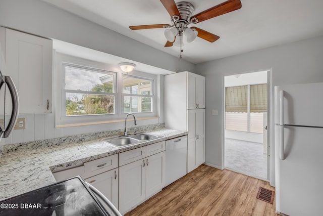 kitchen featuring white appliances, visible vents, light wood-style flooring, white cabinetry, and a sink