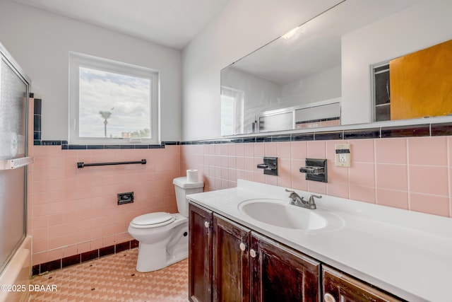 bathroom featuring wainscoting, combined bath / shower with glass door, vanity, and toilet