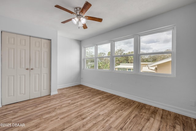 unfurnished bedroom featuring a ceiling fan, a closet, baseboards, and light wood finished floors