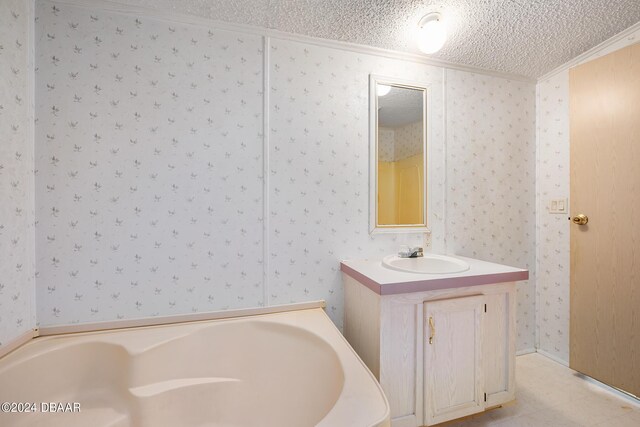 bathroom featuring vanity, crown molding, a textured ceiling, and a tub to relax in