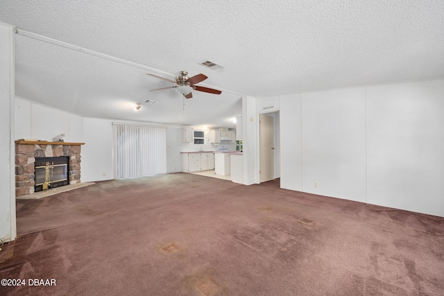 unfurnished living room with a stone fireplace, vaulted ceiling, a textured ceiling, carpet floors, and ceiling fan