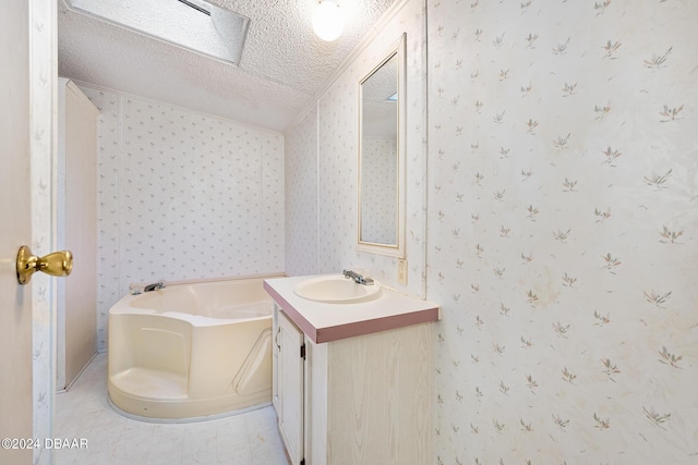 bathroom featuring vanity, a bathtub, and a textured ceiling