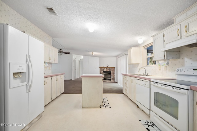 kitchen featuring a fireplace, sink, white cabinets, a center island, and white appliances