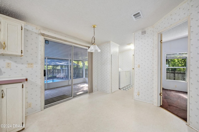 unfurnished dining area featuring washing machine and dryer and a textured ceiling