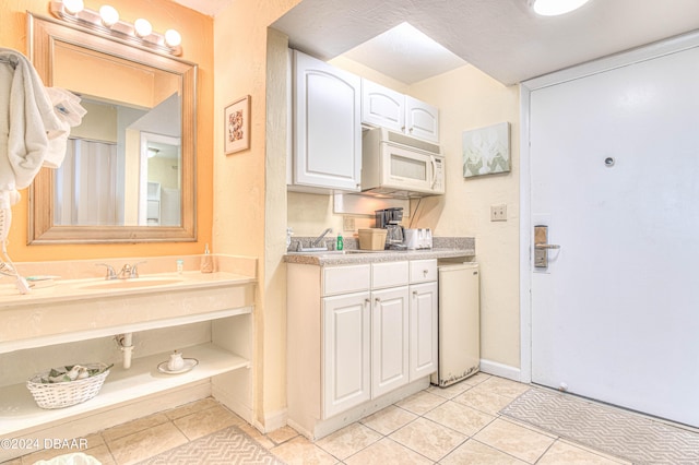 kitchen featuring white cabinetry, sink, and light tile patterned floors