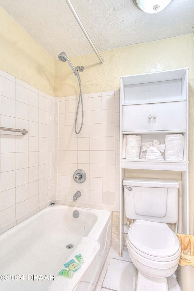 bathroom with tile patterned floors, tiled shower / bath, a textured ceiling, and toilet