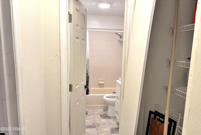 full bathroom with  shower combination, stone finish floor, and toilet