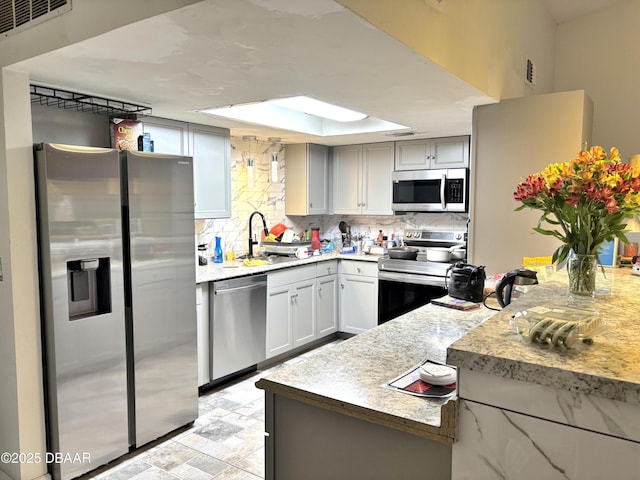 kitchen with stainless steel appliances, visible vents, a sink, and tasteful backsplash