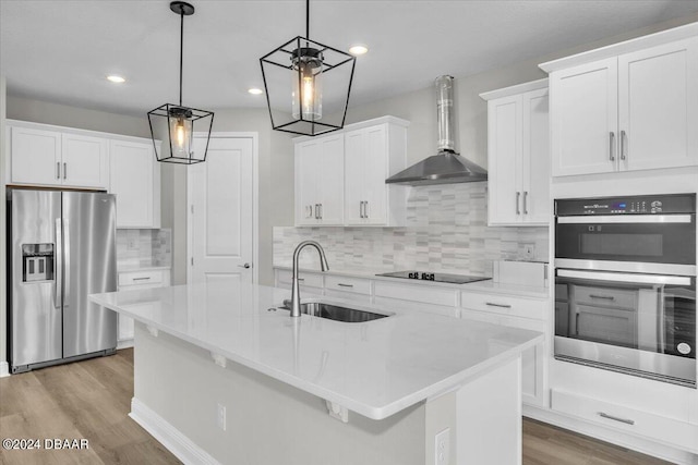 kitchen featuring stainless steel appliances, wall chimney exhaust hood, white cabinets, and pendant lighting