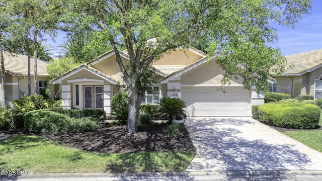 438 Harbour Town Ln, Ormond Beach, FL 32174 - obstructed view of property with an attached garage, stucco siding, driveway, french doors, and a tiled roof