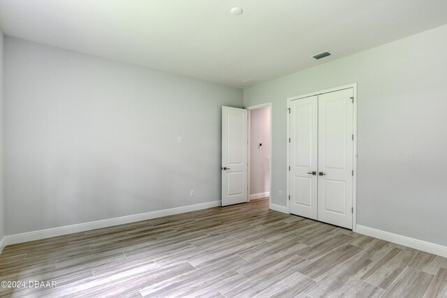 unfurnished bedroom with light hardwood / wood-style flooring and a closet