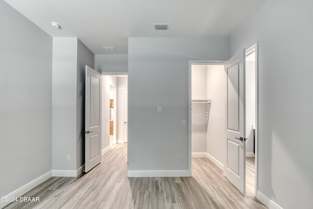 unfurnished bedroom featuring a closet, a walk in closet, and light hardwood / wood-style floors