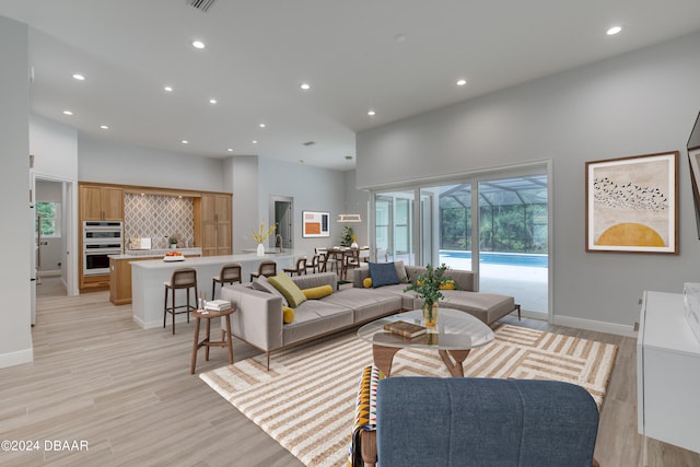 living room featuring a towering ceiling and light wood-type flooring