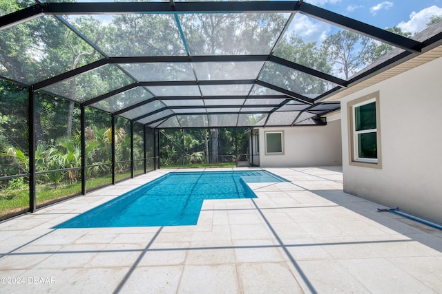 view of pool with glass enclosure and a patio