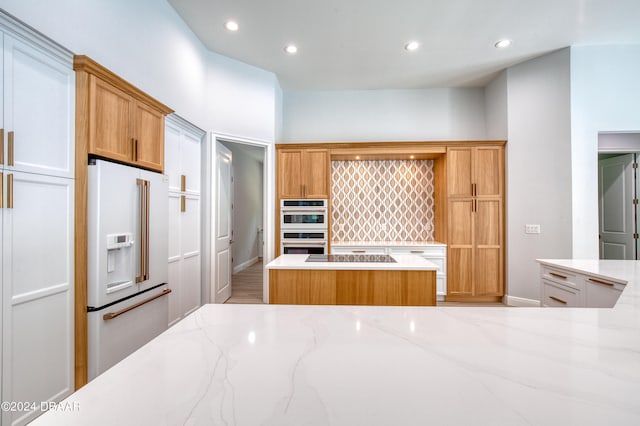 kitchen featuring high end fridge, light hardwood / wood-style floors, double oven, and light stone countertops