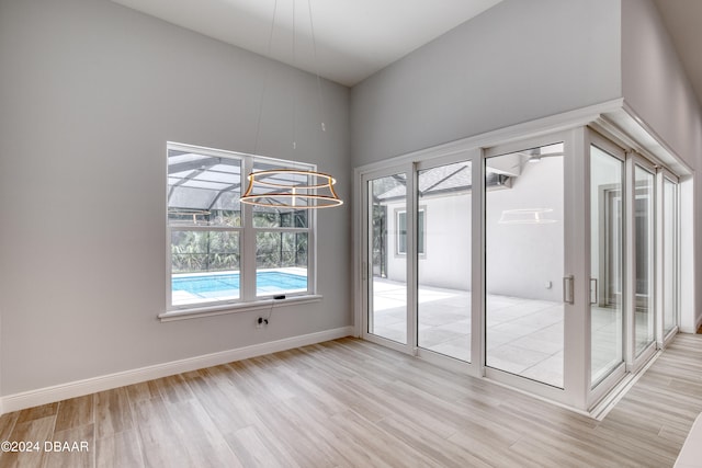 spare room with a high ceiling, light wood-type flooring, and a chandelier