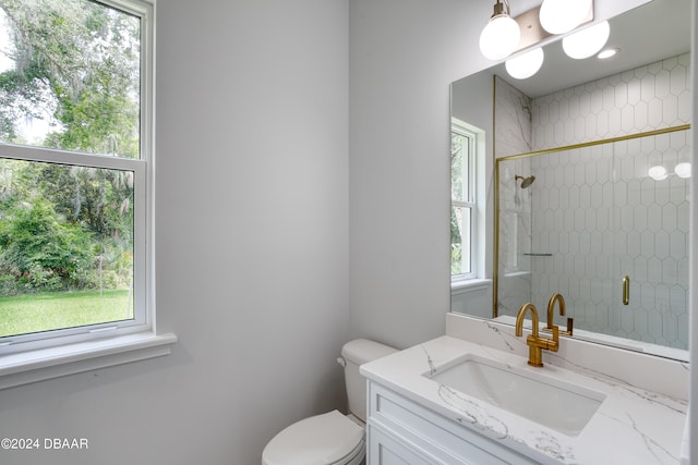 bathroom with toilet, vanity, and a tile shower