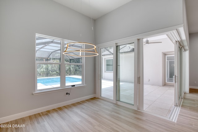 spare room with a towering ceiling, light wood-type flooring, and ceiling fan