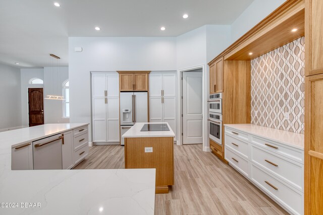 kitchen with white refrigerator with ice dispenser, a kitchen island, white cabinetry, light stone countertops, and light hardwood / wood-style floors