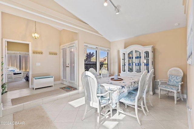 dining space with rail lighting, light tile patterned floors, lofted ceiling, and a notable chandelier