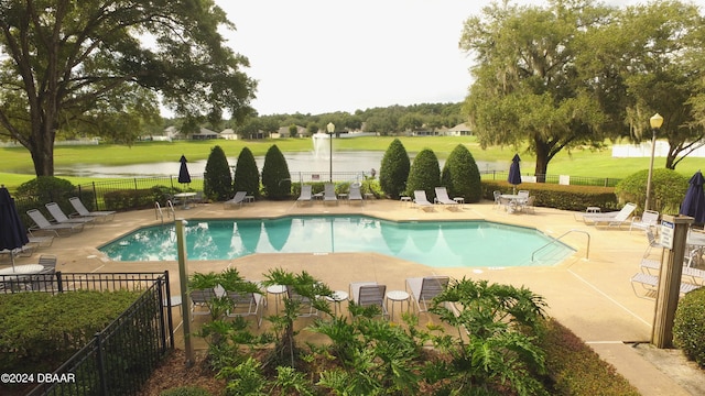 view of swimming pool featuring a yard, a water view, and a patio area