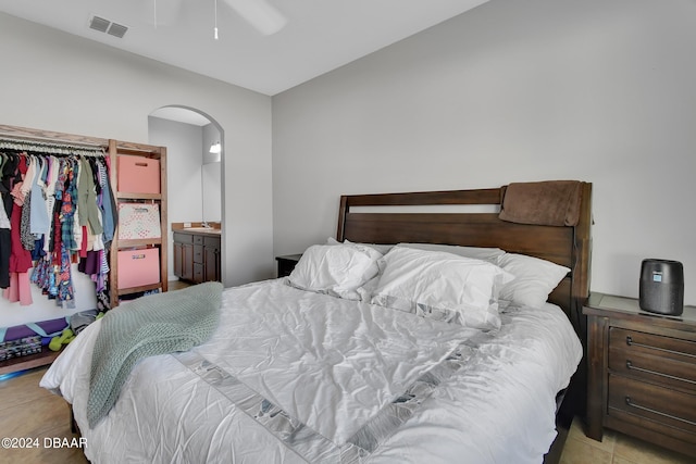 tiled bedroom with ensuite bathroom and ceiling fan