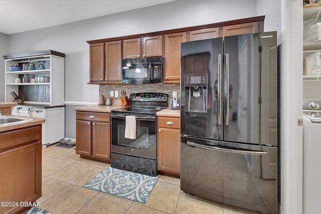 kitchen with light tile patterned floors, black appliances, and tasteful backsplash