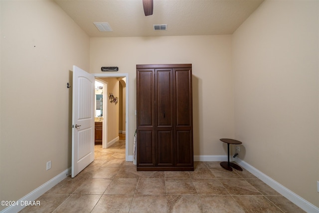 washroom with ceiling fan, a textured ceiling, and light tile patterned flooring