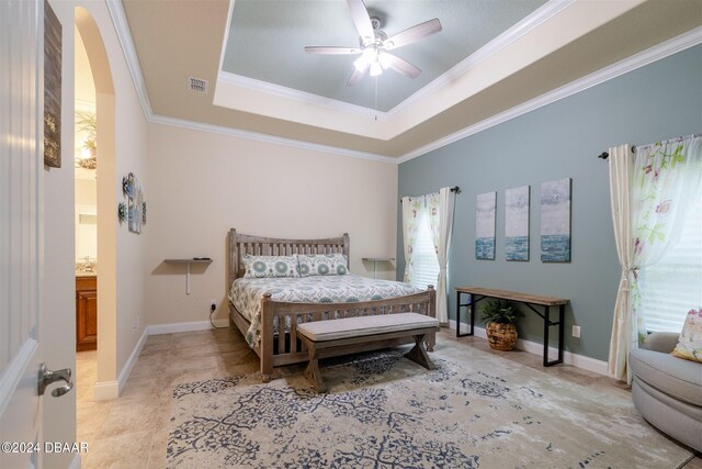 bedroom with ceiling fan, ensuite bath, crown molding, and a tray ceiling