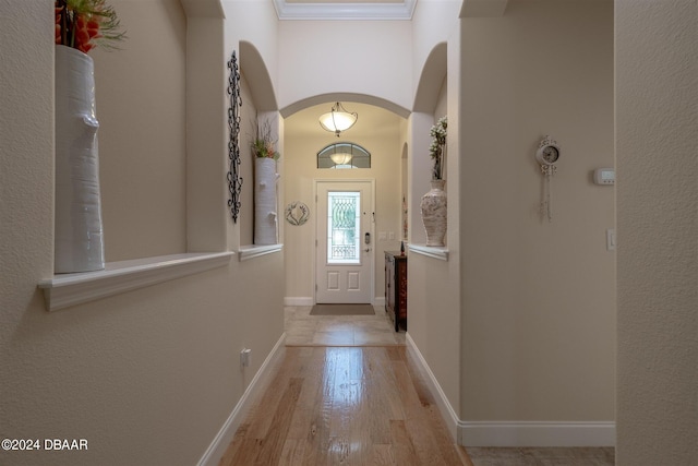 doorway to outside with light wood-type flooring and crown molding