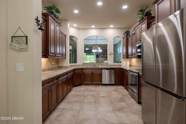 kitchen with stainless steel appliances, backsplash, decorative light fixtures, sink, and an inviting chandelier