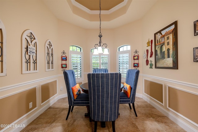 dining area with a notable chandelier, ornamental molding, and a raised ceiling