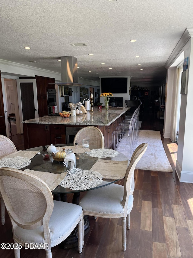 dining area with baseboards, wood finished floors, a textured ceiling, and visible vents