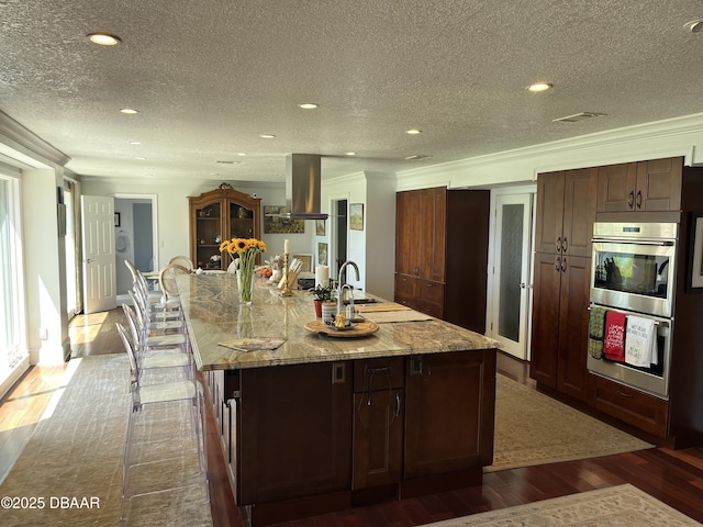 220 John Anderson Dr, Ormond Beach, FL 32176 - kitchen featuring double oven, dark wood-type flooring, island range hood, a textured ceiling, and a large island with sink