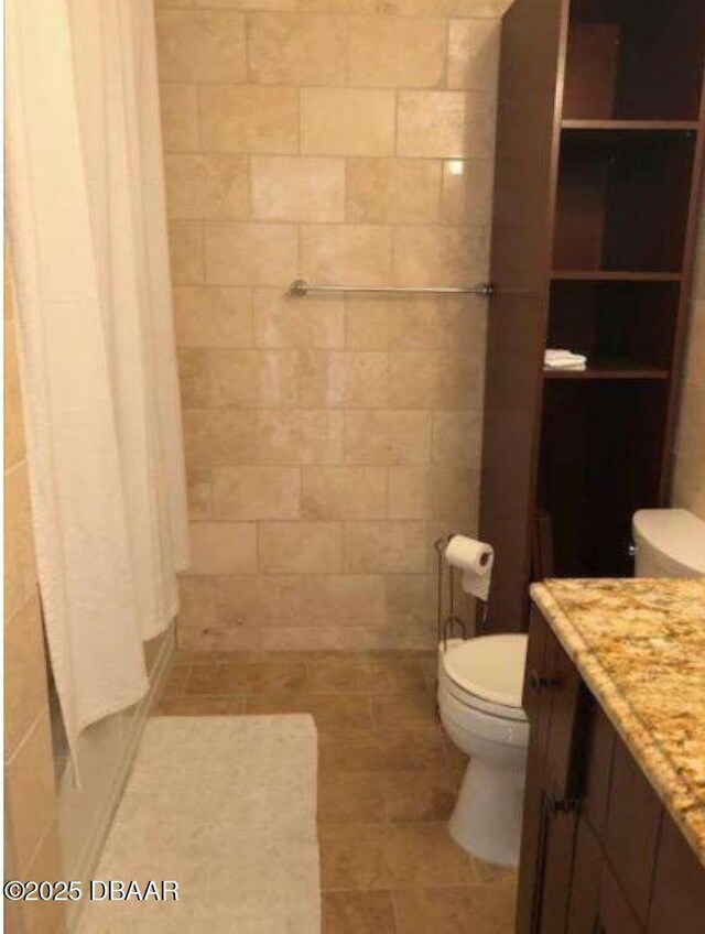 full bathroom featuring toilet, vanity, and a tile shower