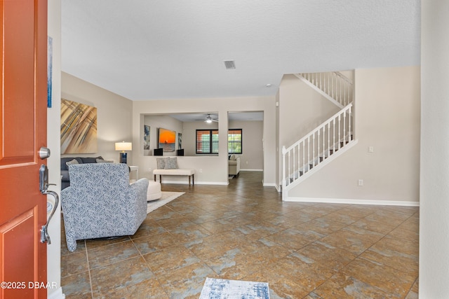 foyer with visible vents, ceiling fan, stairs, and baseboards