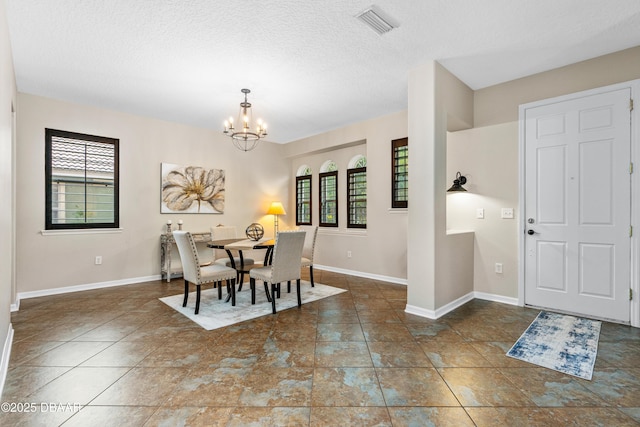 dining area with a textured ceiling, a healthy amount of sunlight, baseboards, and a chandelier