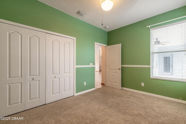 unfurnished bedroom featuring a closet, light carpet, and a textured ceiling