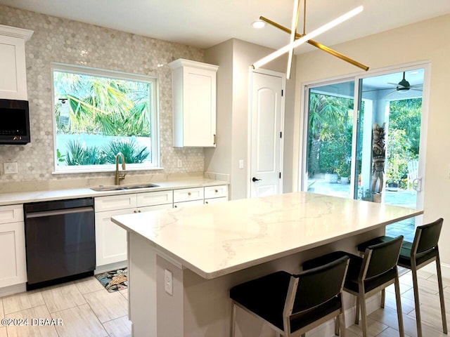 kitchen with white cabinets, sink, ceiling fan, stainless steel dishwasher, and light stone countertops