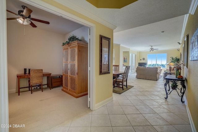 hallway featuring a textured ceiling, light tile patterned flooring, and crown molding