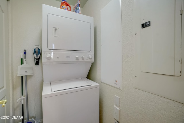 washroom featuring electric panel and stacked washer and clothes dryer