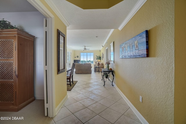 corridor featuring a textured ceiling, light tile patterned floors, and ornamental molding