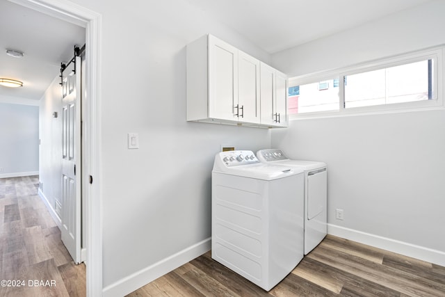 laundry room featuring a barn door, wood finished floors, cabinet space, and baseboards