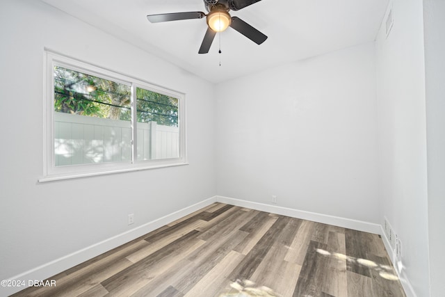 unfurnished room with visible vents, wood finished floors, baseboards, and ceiling fan